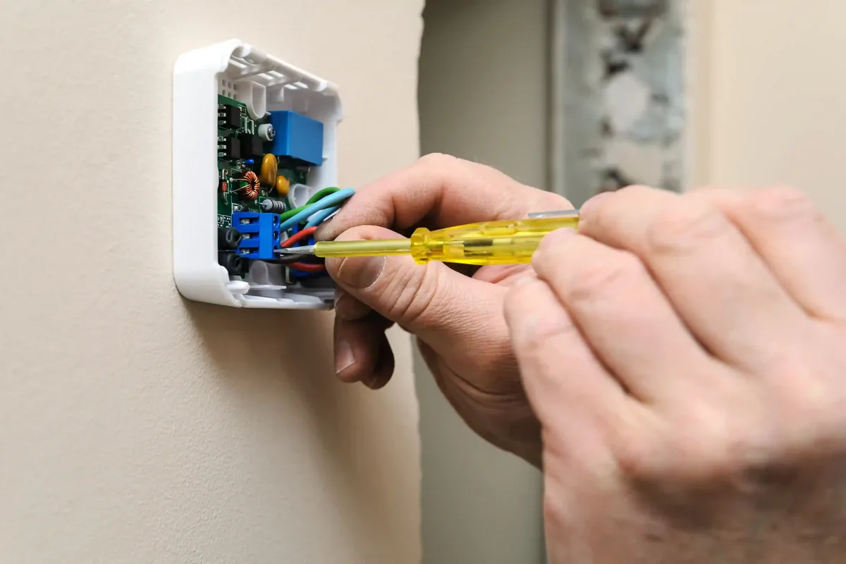 Hand adjusting a thermostat, representing HVAC service intent and local SEO content